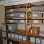 Shelves filled with grey archival boxes and brown cardboard boxes.