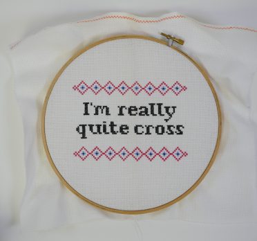 Embroidery hoop around cross stitch reading 'I'm really Quite Cross